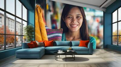 Asian woman smiles in her colorful shop at a bustling market, embodying warmth and friendliness as a proud entrepreneur welcoming tourists and locals with a genuine smile Wall mural