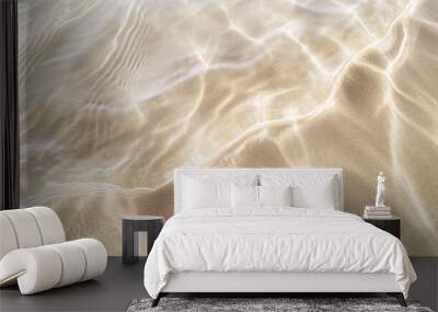 Close-up image capturing the peaceful interaction between clear, shallow waters and the soft sands of a tranquil beach, creating delicate ripples and patterns in the sunlight Wall mural