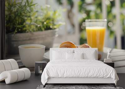 Delicious breakfast setup featuring freshly baked croissants, a cup of coffee, and a glass of orange juice served on an outdoor terrace basked in morning sunlight Wall mural