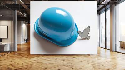 Isolated blue hard hat next to a white peace dove pin, representing construction safety and peace, set on a clean white background with a soft shadow underneath the objects Wall mural