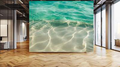 Serene and close-up view of crystal clear turquoise sea waters shimmering under sunlight, with subtle waves creating a rippled texture over soft sandy ocean floor Wall mural