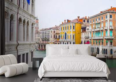 Striped and wooden mooring poles along sides of Grand Canal in Venice, Italy. Hotel, Church with dome top, other colorful Venetian gothic architecture buildings and a docked boat in background. Wall mural