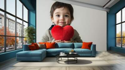 a child of Kazakh nationality holding a plush heart in his hands. On a light background. This is a promotional photo with space for text to advertise an appointment with a pediatric cardiologist Wall mural