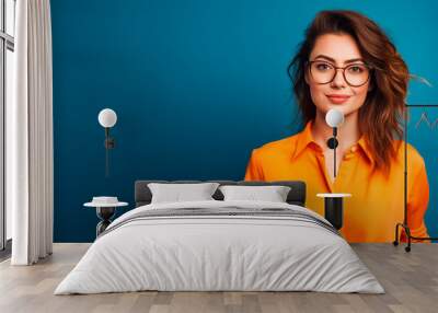 a young woman with glasses wear a orange top on blue background  Wall mural