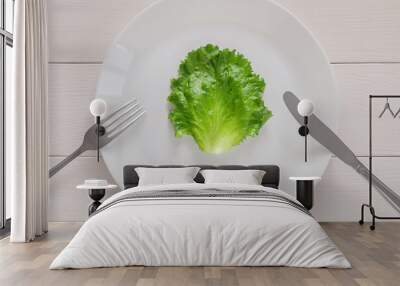 leaf lettuce on white plate with fork and knife, top view Wall mural