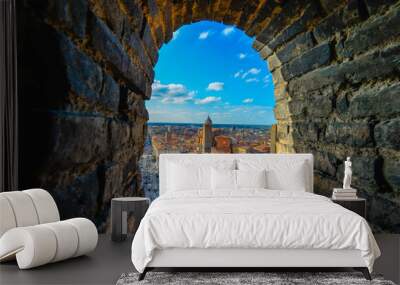 Views from Garisenda tower in Bologna, Italy throug a window to he city center with a surveillance camera in the foreground and the bricks of the tower as the natural frame Wall mural