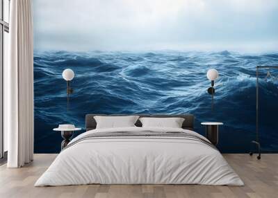 Ocean waves crashing against a rocky coast, white foam and blue water under a dramatic sky Wall mural