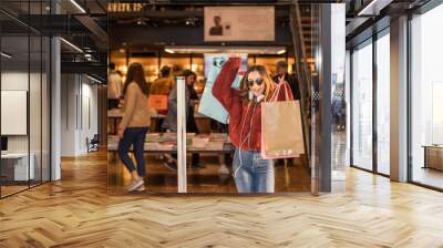 Beautiful young woman exits from clothes Shop Wall mural