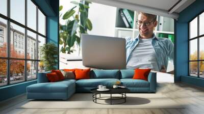 Smiling young man working at home Wall mural