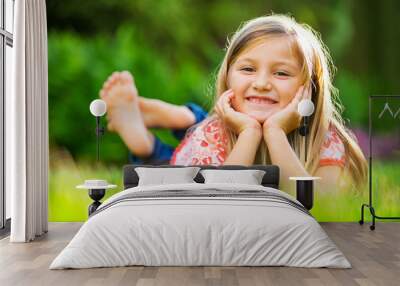 portrait of a smiling little girl lying on green grass Wall mural