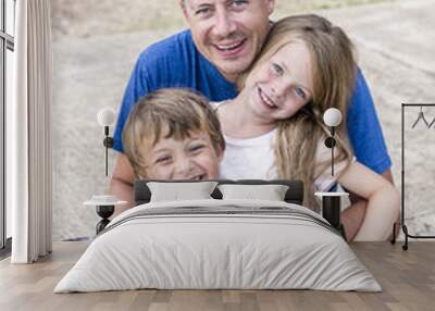 Father with children cuddling on the beach Wall mural