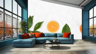 many fresh oranges and green leaves on white crumpled paper background Wall mural