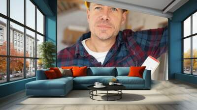 Portrait of construction worker on building site with yellow safety helmet and checkered shirt in an interior room or loft Wall mural