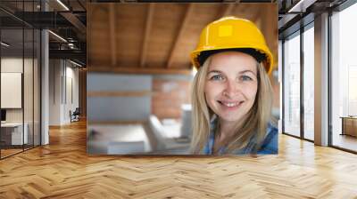 Portrait of pretty young female architect with yellow safety helmet and blue shirt in loft Wall mural