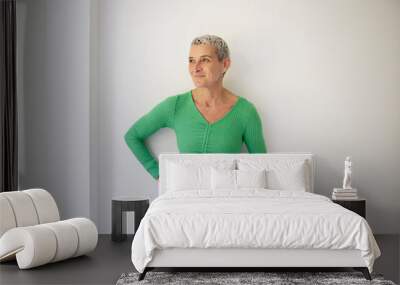 pretty, strong, confident, slim middle-aged woman with short, white, light hair stands in front of white background and represents vegan life Wall mural