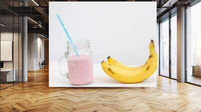 fresh cold pink smoothie on white background with blue straw with bananas Wall mural