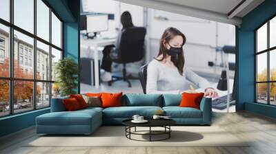 Woman wearing protective mask in office Wall mural