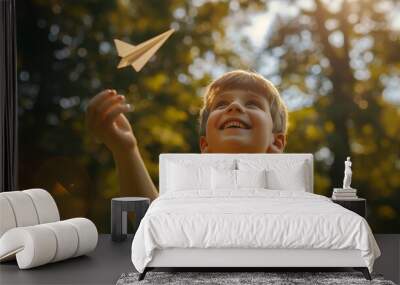 A boy with a happy grin, flying a paper airplane in the park. Wall mural