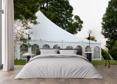 a white wedding tent set up in a lawn surrounded by trees and with the sides down Wall mural