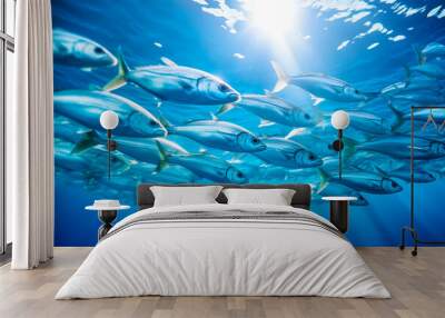 A school of silver fish swimming in the blue ocean with sunlight filtering through. Wall mural