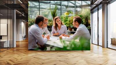 Business team in a meeting inside a greenhouse, discussing strategies on sustainability and leadership. Wall mural