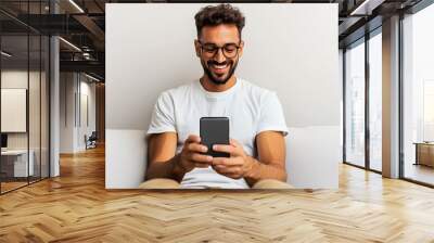 A man is sitting on a couch and smiling while holding a cell phone Wall mural