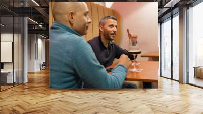 Two men are sitting at a table with wine glasses and a cell phone Wall mural