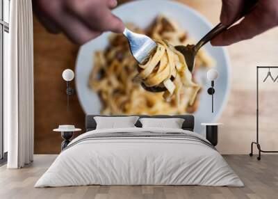 High angle closeup shot of a person reeling up the pasta with a spoon and a fork Wall mural