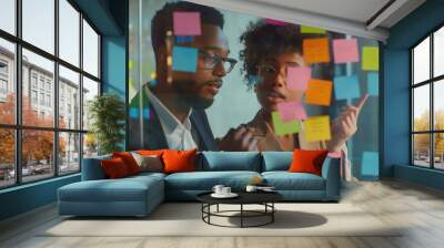 Young mixer race businesswoman manager explaining strategy ideas on sticky notes on glass wall to male African American colleague looking at strategy scrum presentation. Business project planning Wall mural