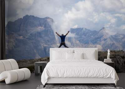 Man jumping celebrating success with the view of the Dolomites mountains. Wall mural