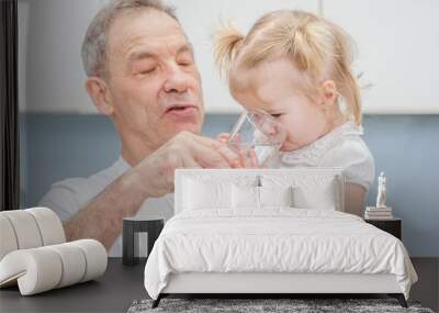 Grandfather gives water to a baby girl Wall mural