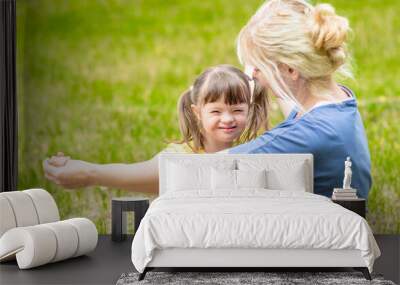 Happy family. Little girl with syndrome down and her mother play together in a summer park Wall mural