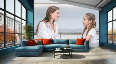 Happy family. Smiling girl and her mom are looking at each other and talking while sitting at home Wall mural