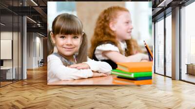 Little girl sitting and studying at school class Wall mural