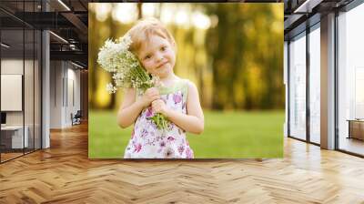 nice little girl with flowers on the grass in summertime Wall mural