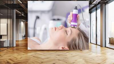 Woman receiving electroporation phonophoresis facial therapy at beauty spa salon. Hardware face cleaning procedure. Rejuvenating facial treatment Wall mural