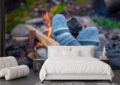 Woman warming feet in socks around bonfire Wall mural