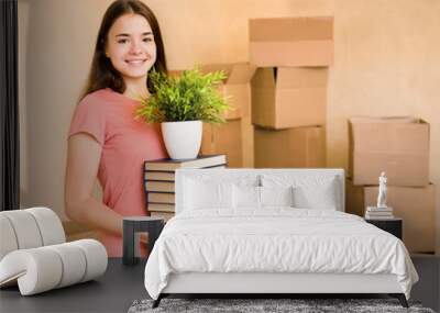 Young woman moving house to college, holding pile books and plan Wall mural