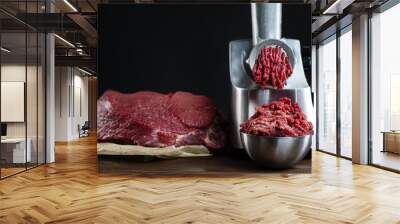 The meat is put in the meat grinder and minced  comes out of it, next to it lies a huge piece of beef tenderloin. Minced meat, meat delicacies, fresh craft food. Wall mural