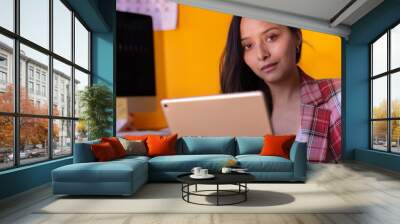 Portrait of a young woman working in an office using a tablet digital device Wall mural