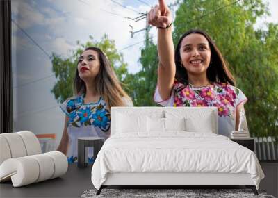 Two young women wearing traditional mexican clothes walking and having fun on the street Wall mural