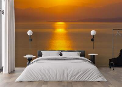 Spectacular sunrise on the horizon with the sea at your feet. Romantic sunrise. Beach sunrises. The sun tries to rise through the clouds in the orange sunrise. Wall mural