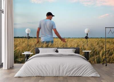 Male farmer standing in a wheat field during sunset. Man Enjoys Nature Wall mural