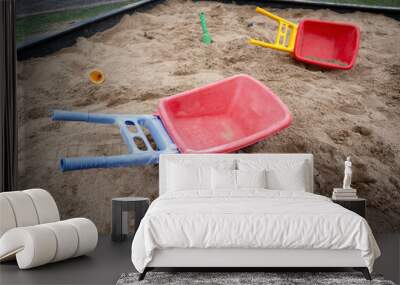 plastic toy wheelbarrows in a sandbox outdoors Wall mural