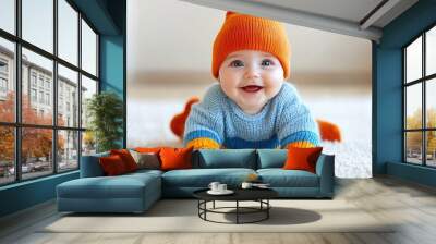 Photo of a happy, smiling baby wearing a colorful sweater and an orange hat, sitting on a white background Wall mural