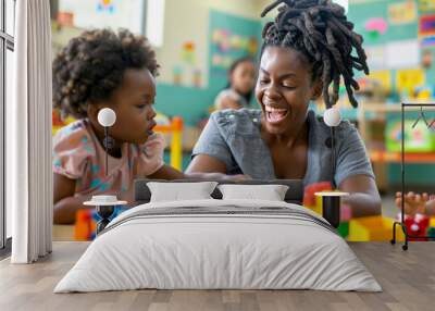 Black woman teacher laughing and playing with little children in a kindergarten, using colourful toys and blocks, develpoing creativity and intelligence. Wall mural