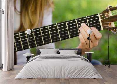 Close-up of a guitar fretboard played by a girl with blonde hair Wall mural