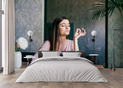 Young lady sitting in a beautiful restaurant, enjoying lunch and gesturing ok sign with her fingers Wall mural