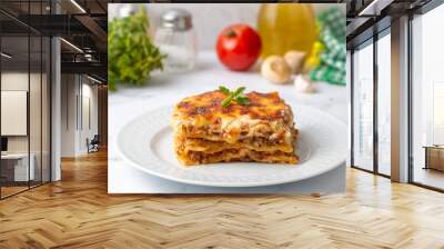 Portion of ground beef lasagna topped with melted cheese and garnished with fresh parsley served on a plate in close view for a menu Wall mural