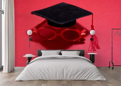 toy miniature maortarboard and red round glasses on red background Wall mural